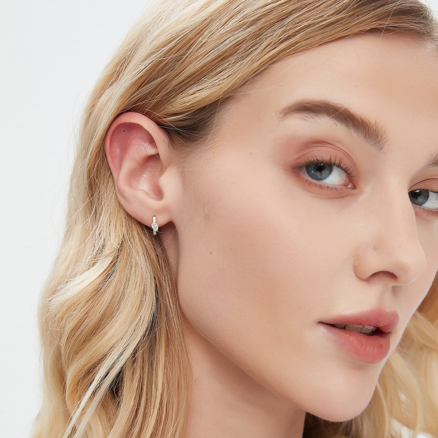 A fashion editorial photograph featuring the Pear Pavé Hoop by LTM Jewels. The model is seen wearing the 8mm 18K gold hoop, highlighting its role as a cinematic heirloom and a sophisticated statement of high-fashion minimalism. The contrast between the radiant pear diamond and the shimmering pavé curve is prominent, illustrating the Amorous Contour design philosophy. This image captures the atmospheric grace of the piece, showing how it adds a structural glow to a luxury collection.