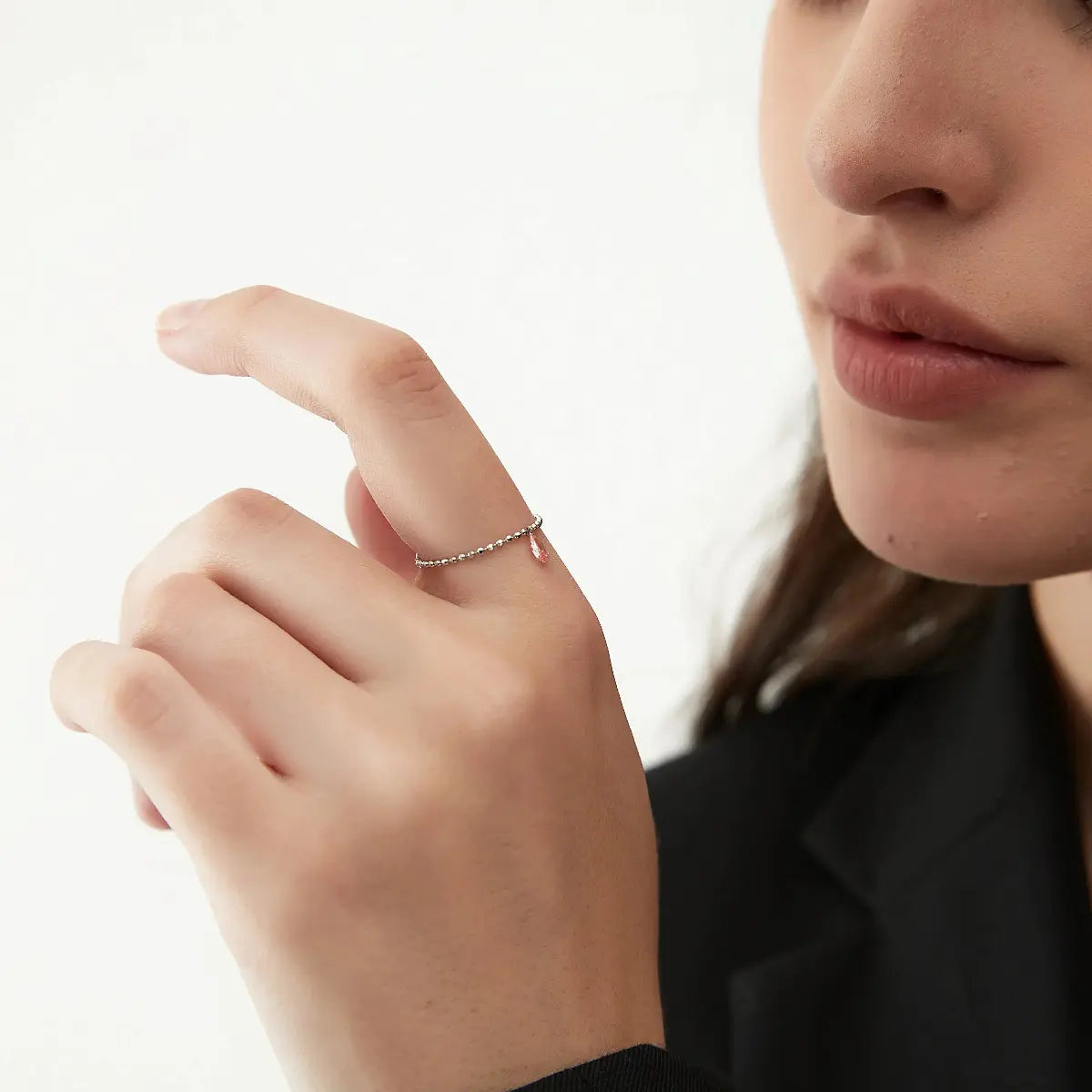 A delicate 18K solid gold chain ring with a pink pear diamond worn on the finger. The flexible Radiant Drift design conforms to the hand, while the laser-drilled floating diamond catches light with every movement. A sophisticated blend of fluid movement and modern architectural luxury.