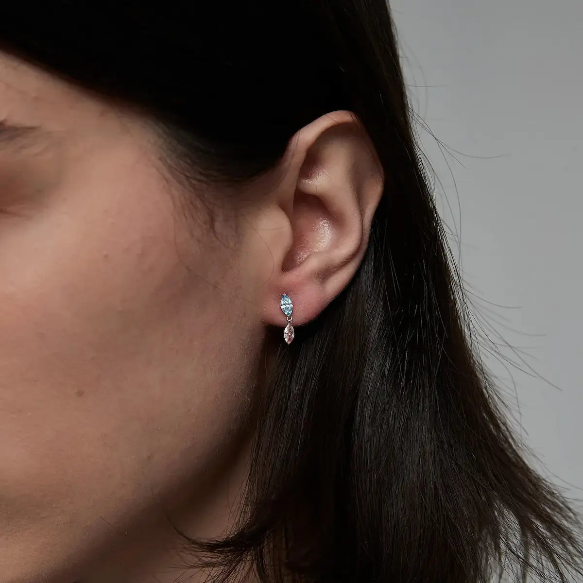 Macro close-up of the Blue and Pink Marquise Dangle Stud handcrafted in solid 18K gold. The suspended floating blue and pink marquise-cut diamonds create uninterrupted brilliance, fluid architectural movement, and refined contemporary fine jewelry craftsmanship.
