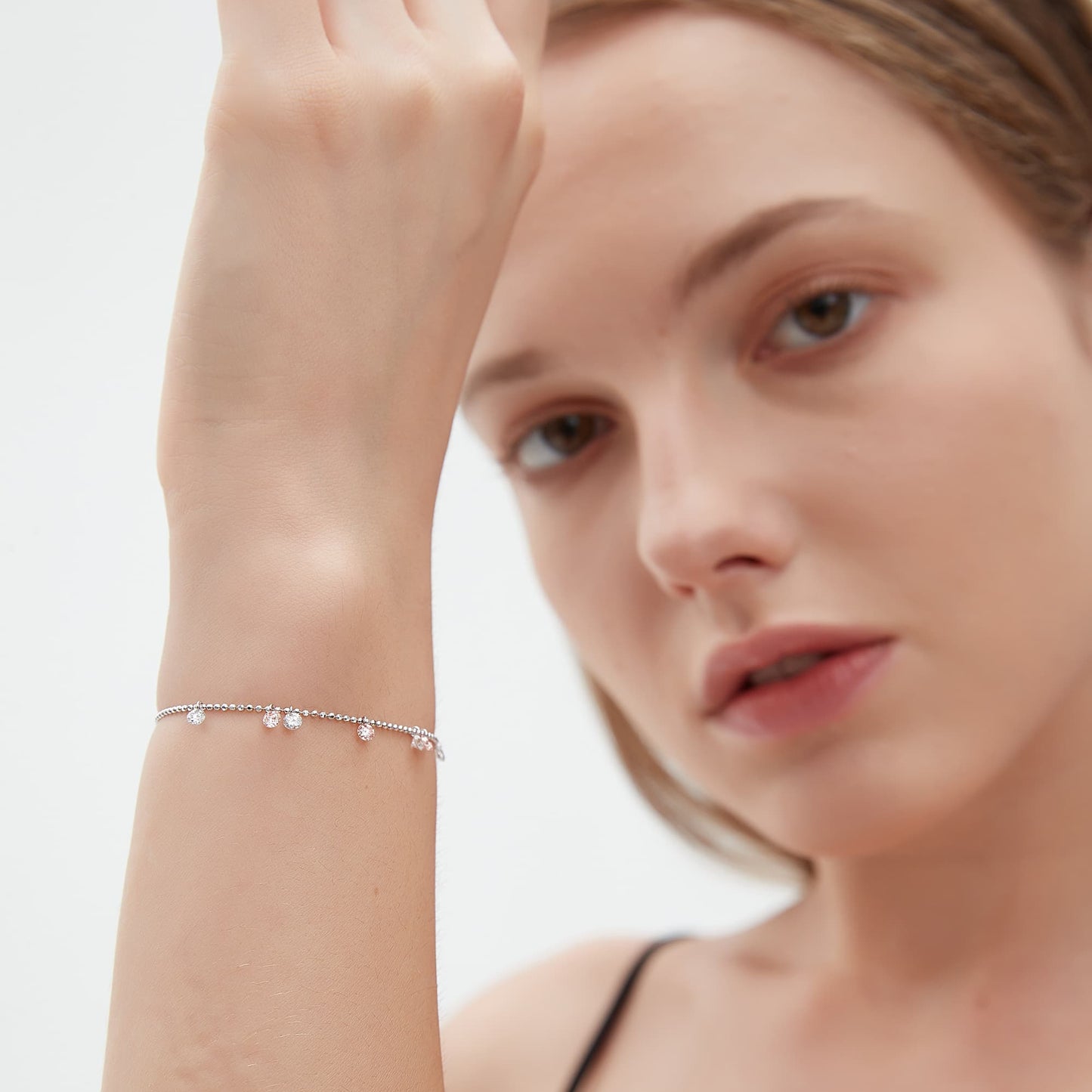 Lifestyle shot of The Rosy Dawn bracelet layered with other fine jewelry