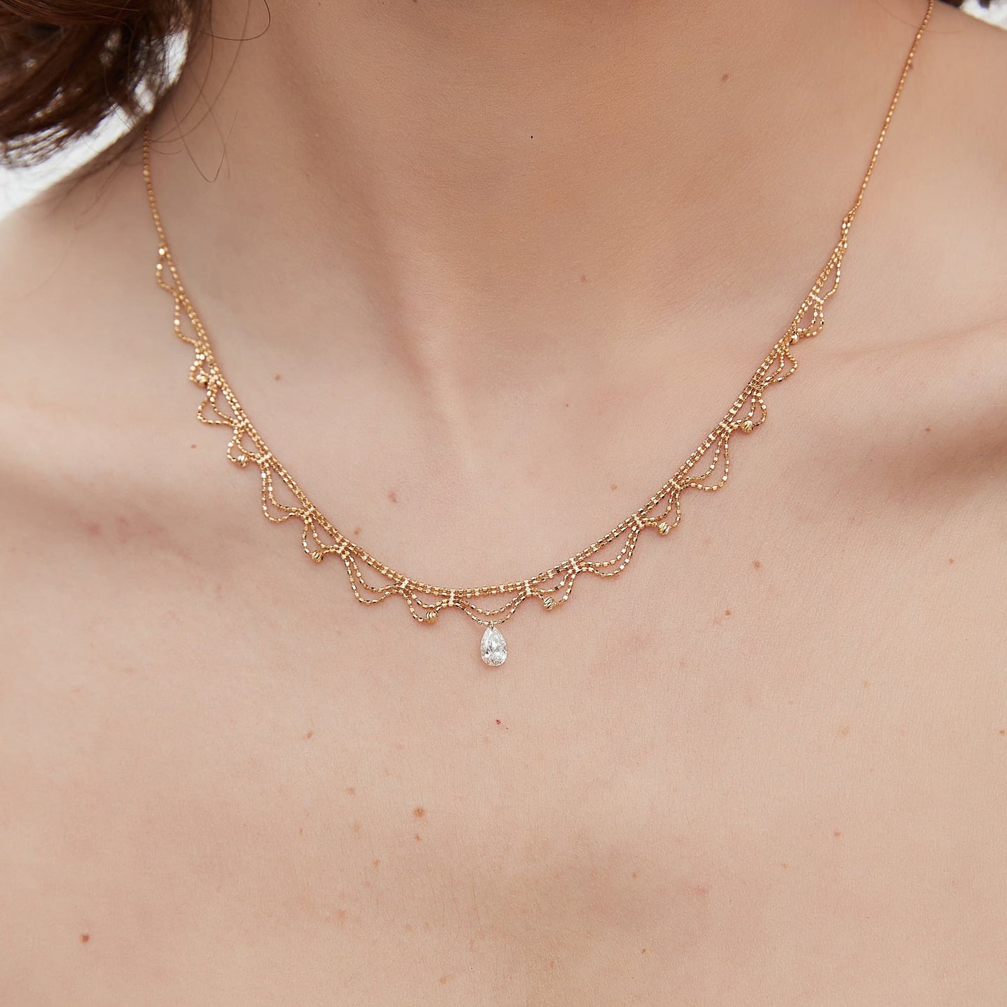 Detail of the 18K gold scalloped lace and signature 0.4ct pear diamond.