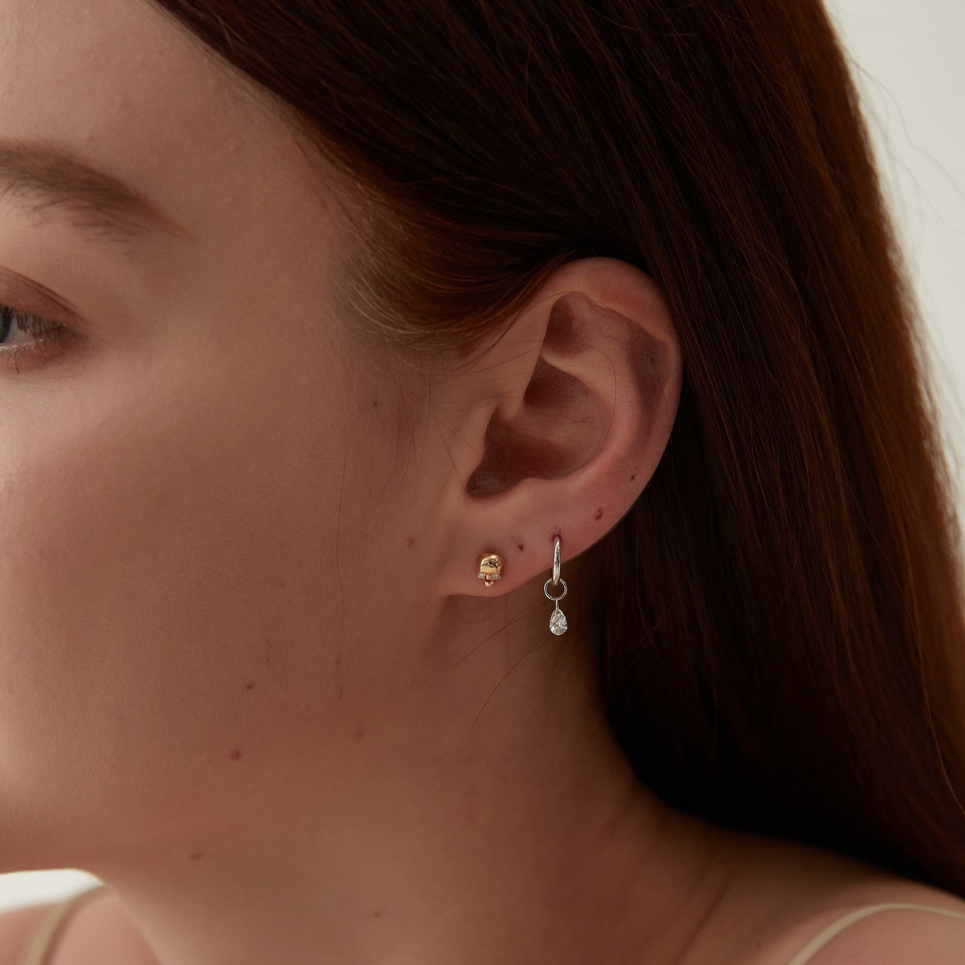 Close-up macro view of the floating pear diamond charm on the ear.