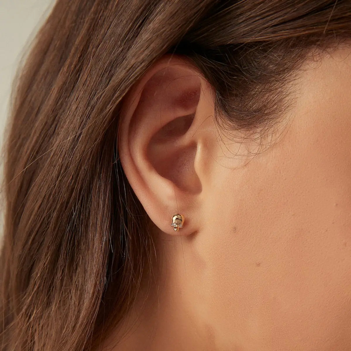 A technical side profile view of the Diamond Skull Threaded Stud. This image highlights the structural integrity of the 18K solid gold AU750 construction and the professional threaded screw back engineered for a secure 24/7 fit. The profile view showcases the depth of the sculpted skull and the length of the post, ensuring comfort and stability for daily wear. The consistent high-polish finish and the alignment of the natural diamond are clearly visible, emphasizing technical quality.