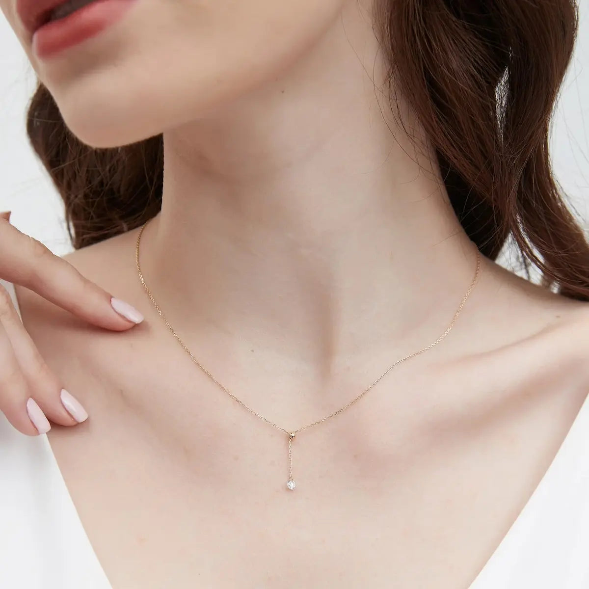 A professional lifestyle photograph showing the Adjustable Round Diamond Necklace styled on a model's neck. The image demonstrates the necklace's versatility, illustrating how the 0.2ct diamond can be repositioned along the 18K solid gold chain to suit different necklines. This perspective highlights the fluid motion of the 'Radiant Drift' design and how the brilliant stone catches light in a real-world setting. Perfect for visualizing its minimalist yet impactful sparkle for daily wear or layering.