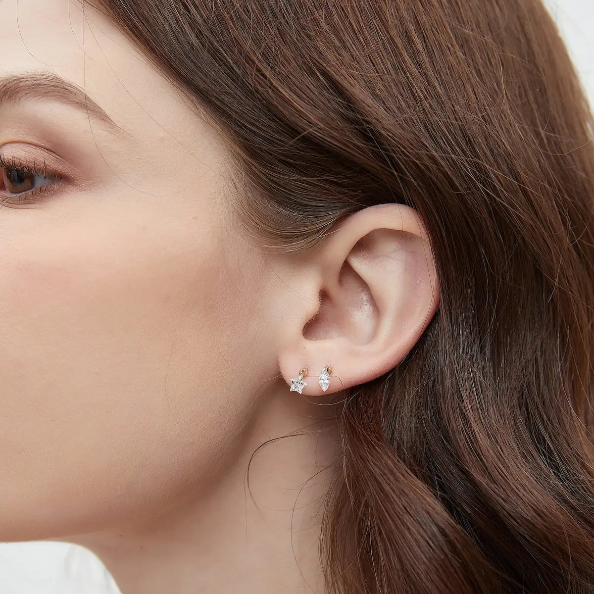 This editorial fashion shot features a model wearing the LTM & CO. Star-Cut Diamond Stud, placing the jewelry within a context of refined, modern elegance. The model’s styling is minimalist and sophisticated, allowing the brilliance of the 18K gold and star-cut lab-grown diamond to take center stage. The image emphasizes the stud’s role as a symbol of conscious luxury and architectural design. The sharp, geometric silhouette of the star-shaped diamond draws the eye, providing a luminous focal point that ref